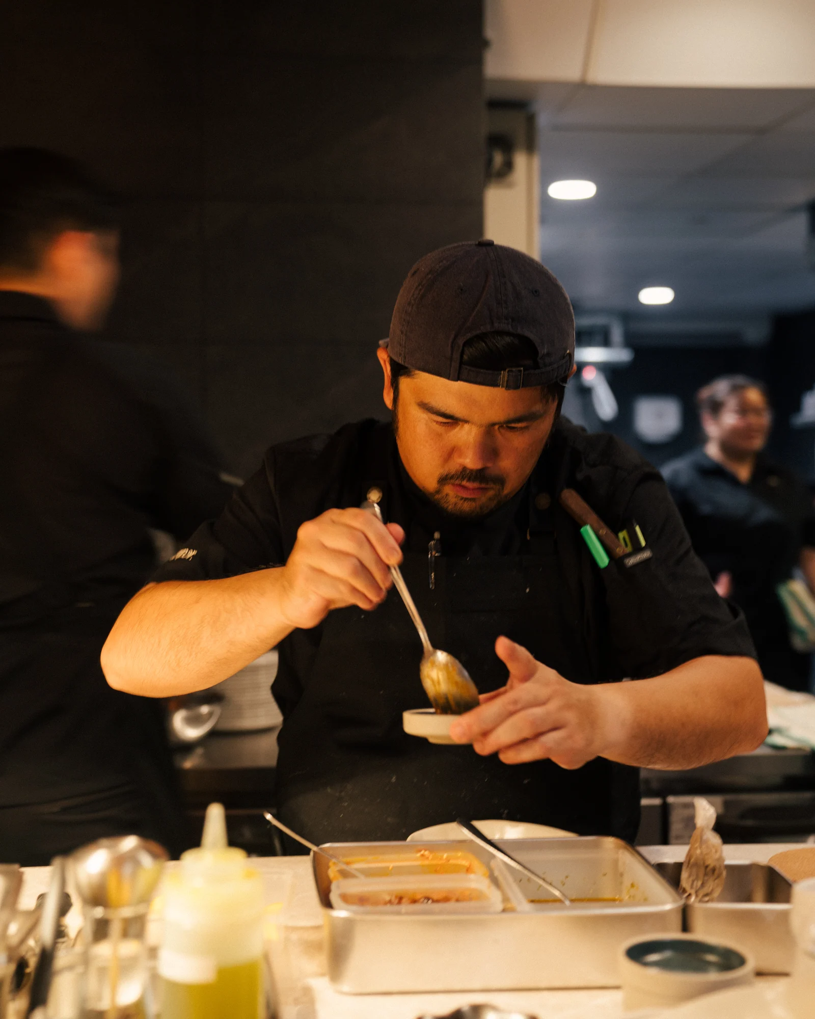 Chef spooning sauce onto a plate at the pass