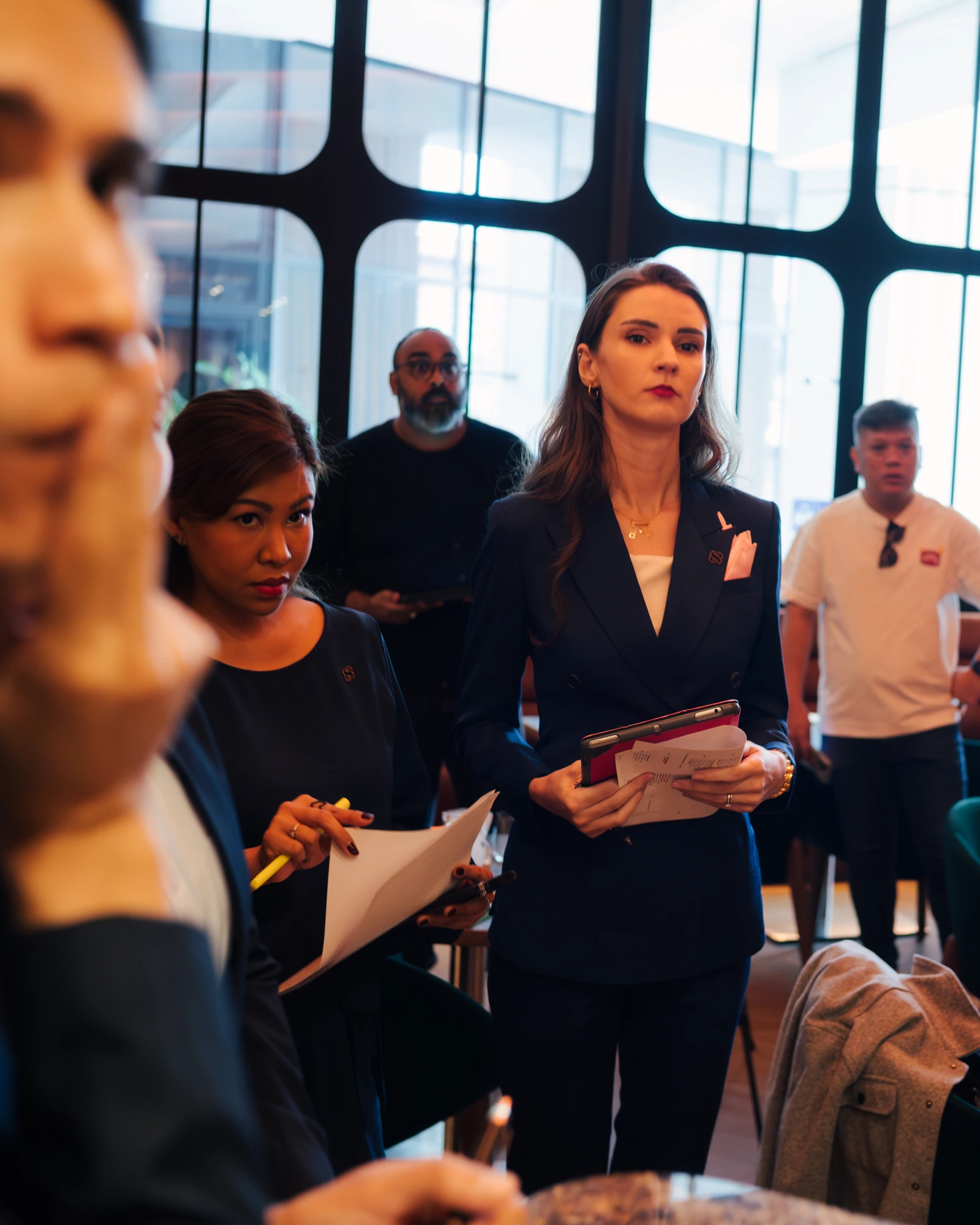 Staff in suits holding notes and tablets during a pre-service briefing