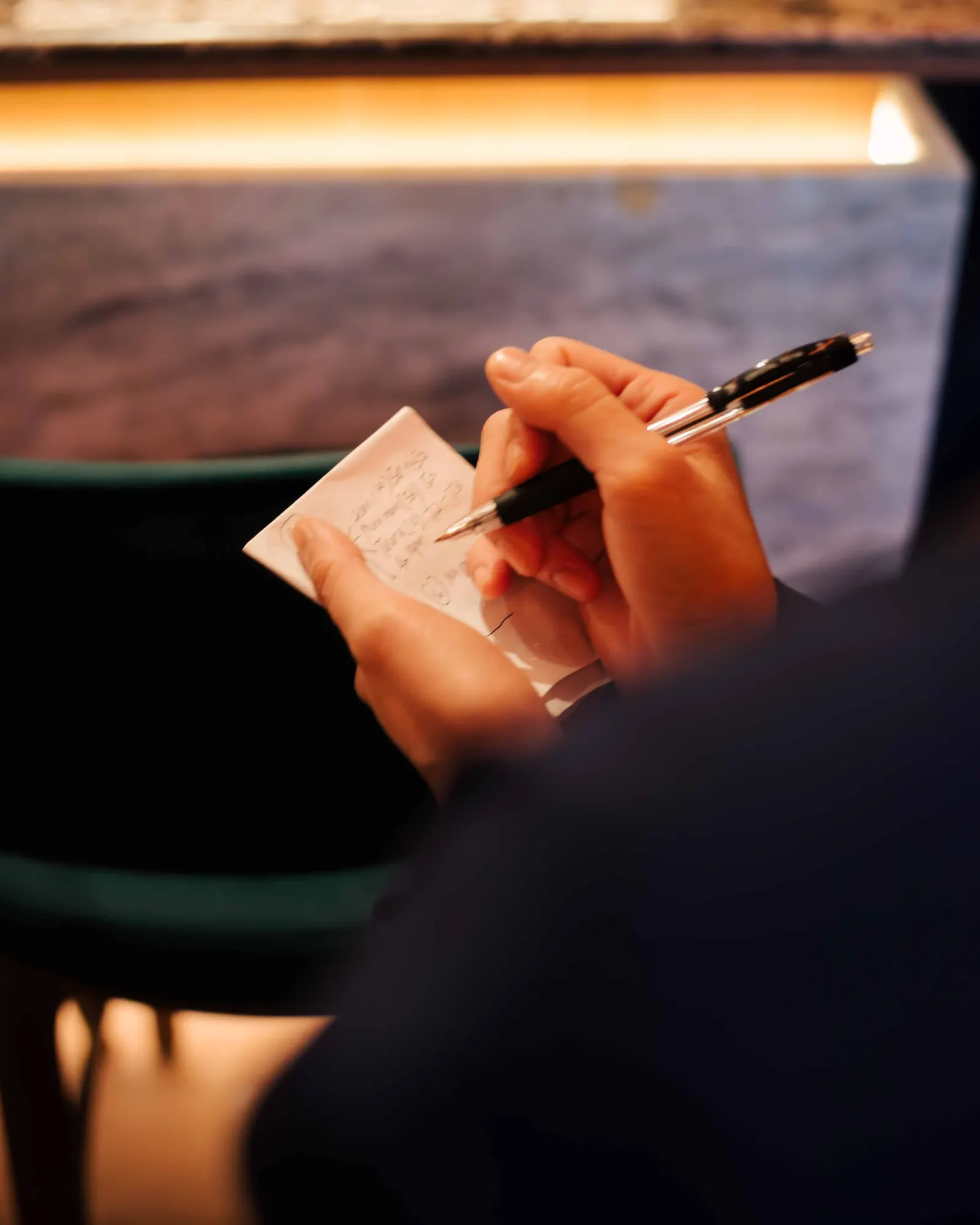 Close-up of a server’s hands writing an order on a small notepad