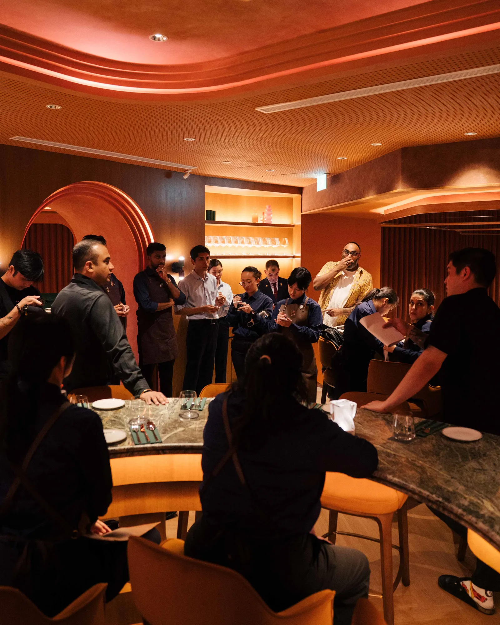 Staff gathered around the curved bar for a pre-service briefing