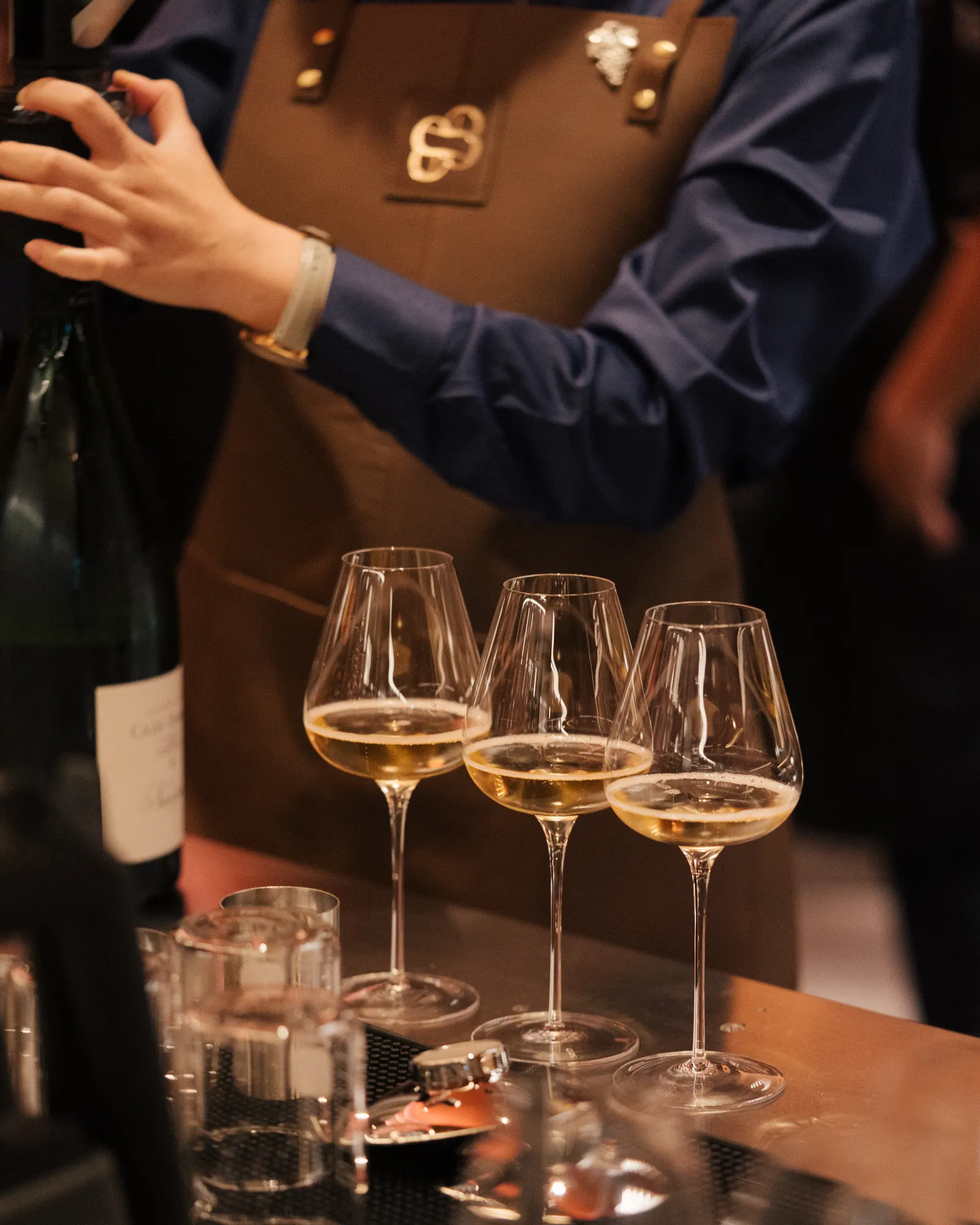 Three glasses of white wine poured on the bar